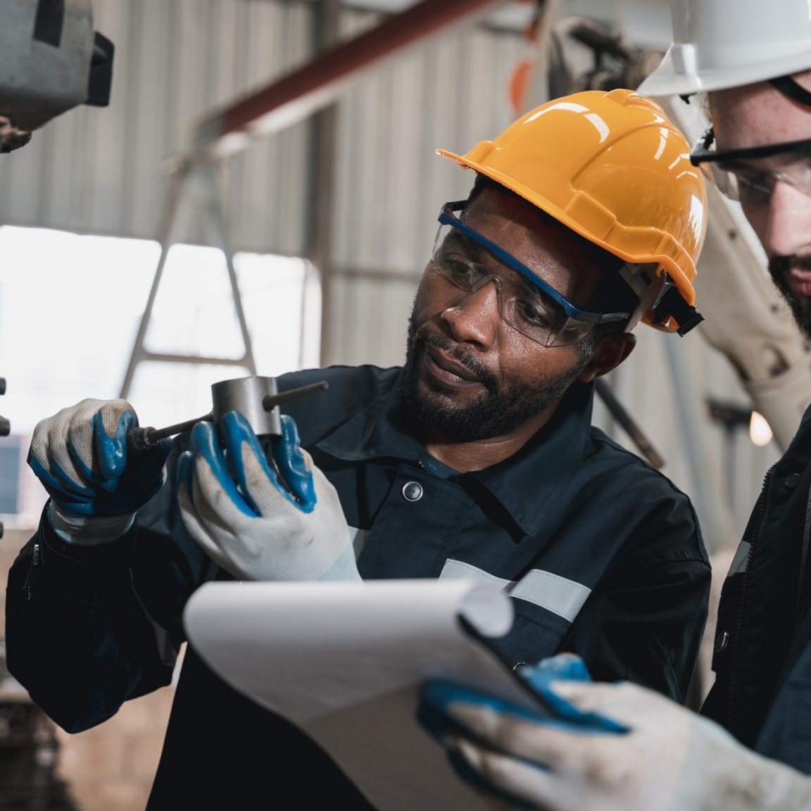 Industrial engineers inspect and perform maintenance on the machines at factory machines.